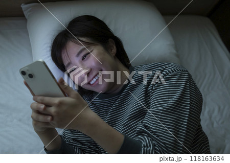 ベッドでスマホを見る女性 ベッドでスマホを見る女性 118163634