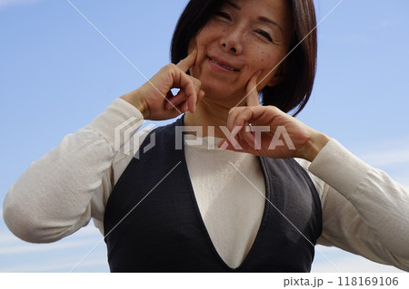 青空の下で寛ぐシニア女性 118169106