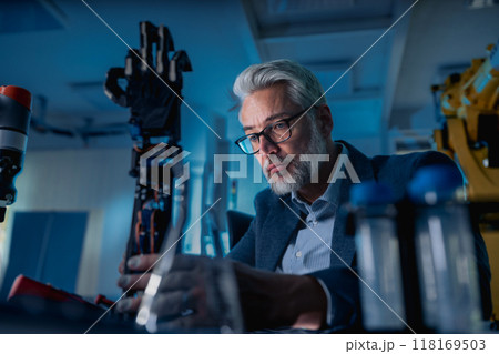 Robotics engineer adjusting, calibring robotic prosthetic hand. Concept of modern technology in medicine. Robotic prosthetics, biomechatronics and neuroscience. 118169503