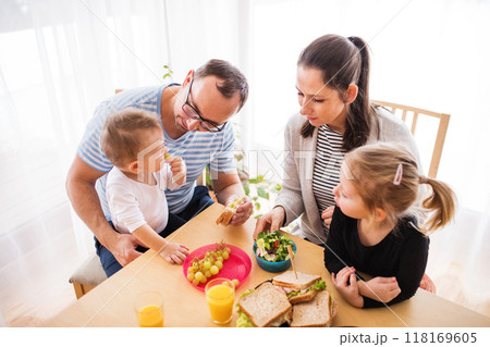 Parents with two children eating a tasty, healthy breakfast in the kitchen. Happy family moment. Parents with two children eating a tasty, healthy breakfast in the kitchen. Happy family moment. 118169605