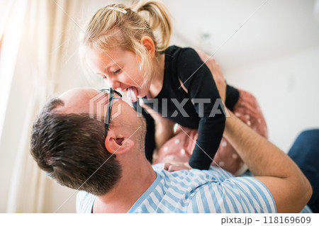 Dad playing with little daughter holding her above him. Girl and father having fun. 118169609