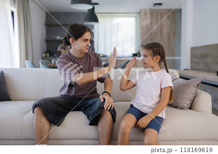 Teenage brother gave high five to his six year old sister after they finish and win game on console.  118169619