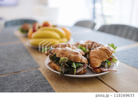 Tasty croissants with ham, cheese, salad, tomato and other healthy ingredients. French breakfast for four person. Plate with food on wooden table Tasty croissants with ham, cheese, salad, tomato and other healthy ingredients. French breakfast for four person. Plate with food on wooden table 118169635