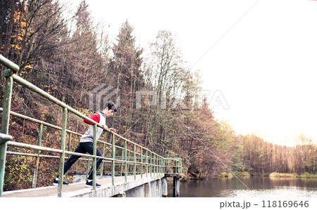 Sporty man preparing for run, stretching in park by lake. Morning workout for young man. 118169646