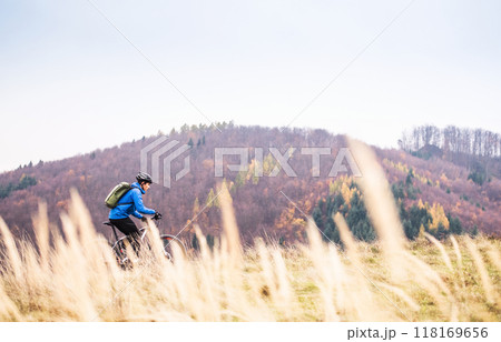 Active man on bike in the middle of beautiful nature, early autumn morning. Concept of healthy lifestyle. 118169656