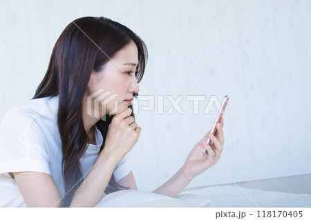 スマホを見て悩む女性 スマホを見て悩む女性 118170405