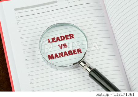 Leader vs manager is shown through a magnifying glass on a blank page of a notebook, a book Leader vs manager is shown through a magnifying glass on a blank page of a notebook, a book 118171361