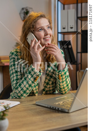 Businesswoman freelancer answering to client on mobile phone call using smartphone and laptop Businesswoman freelancer answering to client on mobile phone call using smartphone and laptop 118171697