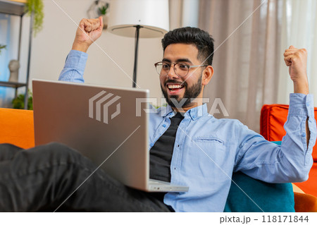 Happy Indian man using laptop receive good news shocked by victory celebrate lottery jackpot victory Happy Indian man using laptop receive good news shocked by victory celebrate lottery jackpot victory 118171844