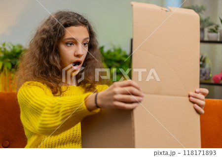 Happy child girl shopper unpacking cardboard box delivery parcel online shopping purchase at home 118171893