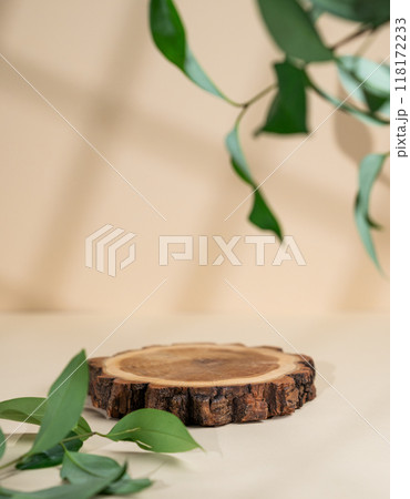 Abstract empty wooden cutting board with shadows and green leaves on a beige background.  118172233