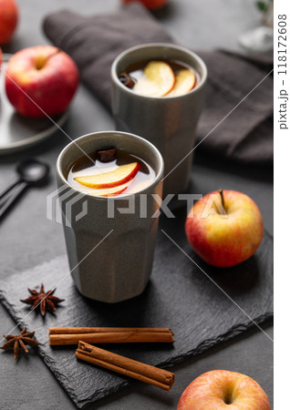 Homemade apple punch or cider with apples and cinnamon in gray cups on a dark background Homemade apple punch or cider with apples and cinnamon in gray cups on a dark background 118172608