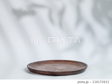 Abstract empty wooden plate with shadows leaves on a gray background. Abstract empty wooden plate with shadows leaves on a gray background. 118172631
