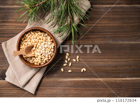 Pine nuts in a bowl  on a dark wooden background with branches of pine needles.  118172634