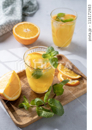 Freshly squeezed juice in a glass with fresh oranges, mint and ice on a light background Freshly squeezed juice in a glass with fresh oranges, mint and ice on a light background 118172983