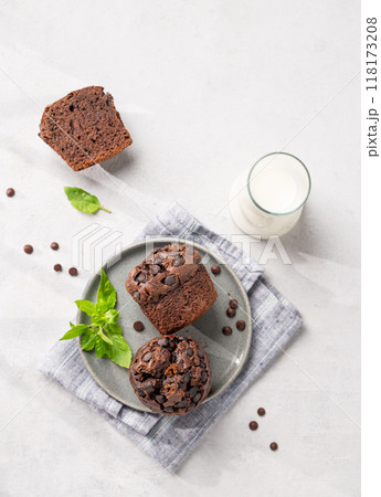 Chocolate muffins on a plate with mint on a light background with milk and morning shadow. 118173208