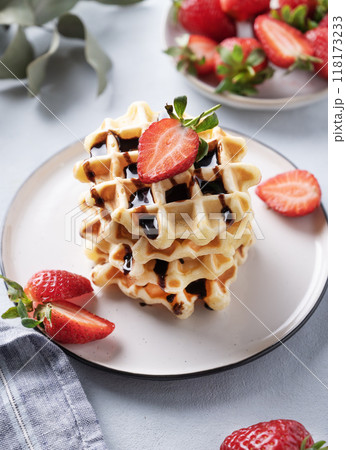 Homemade soft waffles with fresh strawberries and chocolate topping in a stack in a plate Homemade soft waffles with fresh strawberries and chocolate topping in a stack in a plate 118173233