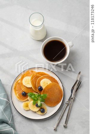 Delicious banana pancakes with fresh fruit slices, berries, mint and honey on a light background Delicious banana pancakes with fresh fruit slices, berries, mint and honey on a light background 118173246