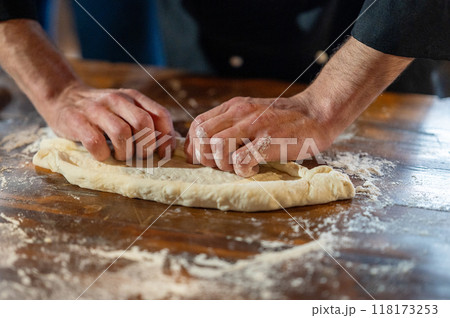 Hands kneading dough on a dark wooden table close up. 118173253