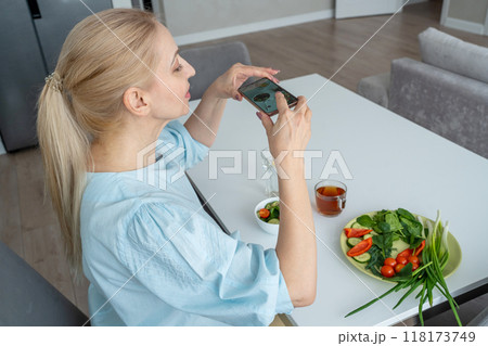 A woman is holding a smartphone and capturing a photo of a nutritious breakfast spread A woman is holding a smartphone and capturing a photo of a nutritious breakfast spread 118173749