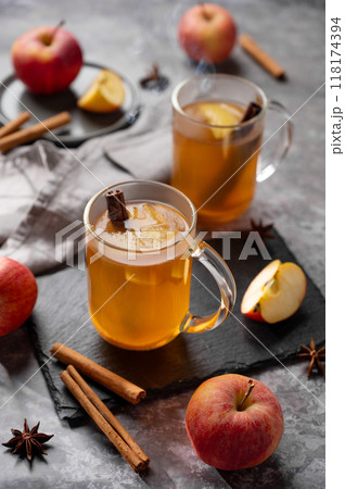 Homemade apple punch with fresh apples, cinnamon and spices in cups on dark background  118174394