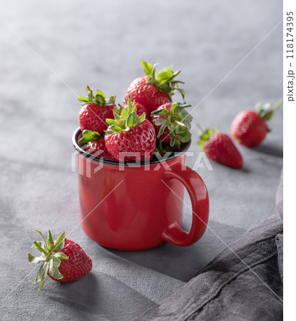 Juicy strawberries in a red cup on a dark background with morning shadows.  118174395