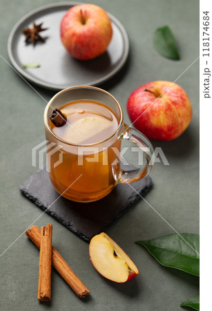 Homemade apple punch with fresh apples, cinnamon and spices in cup on a green background  118174684