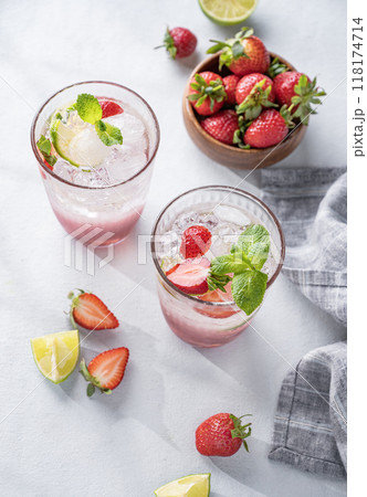 Fresh strawberry mojito in a glass with berries, lime, mint and ice on a light background  118174714