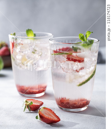 Fresh strawberry mojito in a glass with berries, lime, mint and ice on a light background. Fresh strawberry mojito in a glass with berries, lime, mint and ice on a light background. 118174723