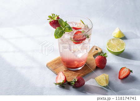 Fresh strawberry mojito in a glass with berries, lime, mint and ice on a light background  118174741