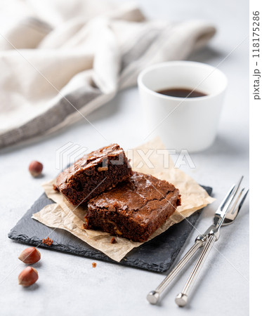 Pieces of chocolate brownies with hazelnuts and salted caramel on baking paper on a light background 118175286