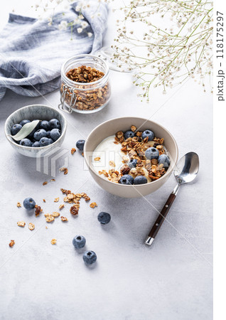 The concept of a healthy breakfast of yogurt, granola and fresh blueberry on a light background The concept of a healthy breakfast of yogurt, granola and fresh blueberry on a light background 118175297