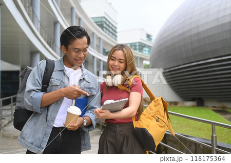 Two college students sharing ideas or discussing something while walking on a university campus 118175364