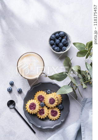 Cappuccino or latte with milk foam in a cup with  homemade berry cookies in a dark plate  118175457