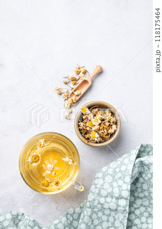 Chamomile herbal tea in a glass cup on a light background with dry flowers and napkin. Chamomile herbal tea in a glass cup on a light background with dry flowers and napkin. 118175464