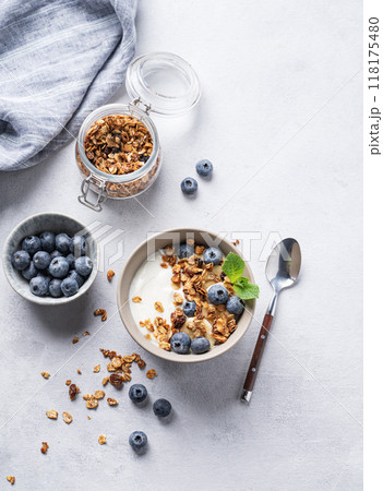 The concept of a healthy breakfast of yogurt, granola and fresh blueberry on a light background. 118175480