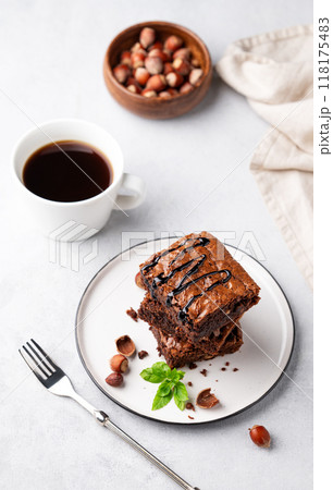 A stack of chocolate brownies with mint, hazelnuts and salted caramel on a white plate A stack of chocolate brownies with mint, hazelnuts and salted caramel on a white plate 118175483