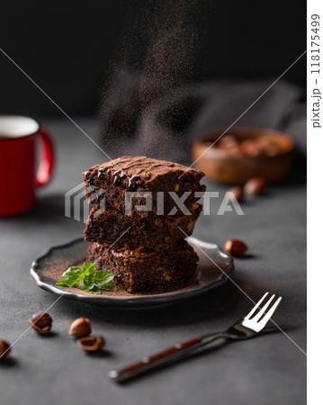 Cocoa pours on to a stack of chocolate brownies with hazelnuts and salted caramel Cocoa pours on to a stack of chocolate brownies with hazelnuts and salted caramel 118175499