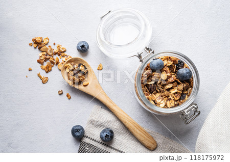 Homemade baked granola with nuts and fresh blueberry in a jar on a light background close up. Homemade baked granola with nuts and fresh blueberry in a jar on a light background close up. 118175972