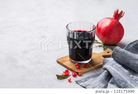 Natural pomegranate juice in a glass on a light background with fresh fruit and napkin.  118175990
