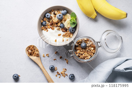 Homemade baked granola with yogurt, blueberries and banana in a bowl on a light background Homemade baked granola with yogurt, blueberries and banana in a bowl on a light background 118175995