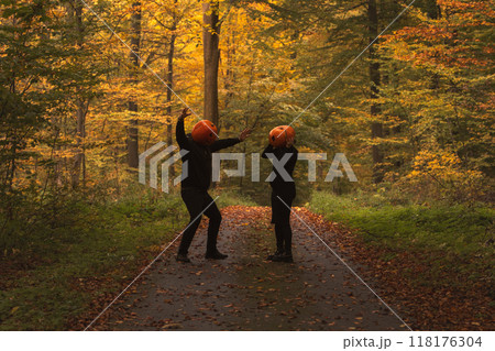 Couple in Pumpkin Heads Amidst Autumn Forest 118176304