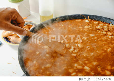 man cooking a spanish fideua in a paella pan man cooking a spanish fideua in a paella pan 118176580