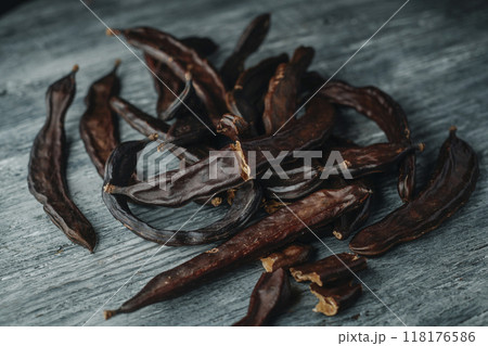 bunch of ripe carob pods on a wooden table 118176586