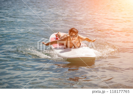 Woman sup sea travel. Sports girl on a surfboard in the sea on a sunny summer day. In a black bathing suit, he sits on a sapa in the sea. Rest on the sea. Woman sup sea travel. Sports girl on a surfboard in the sea on a sunny summer day. In a black bathing suit, he sits on a sapa in the sea. Rest on the sea. 118177765