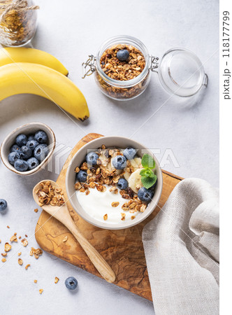 Homemade baked granola with yogurt, blueberries and banana in a bowl on a light background Homemade baked granola with yogurt, blueberries and banana in a bowl on a light background 118177799