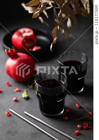 Natural pomegranate juice in a glasses on a dark background with fresh fruit and bouquet.  118177800