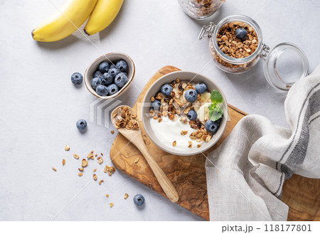 Homemade baked granola with yogurt, blueberries and banana in a bowl on a light background Homemade baked granola with yogurt, blueberries and banana in a bowl on a light background 118177801