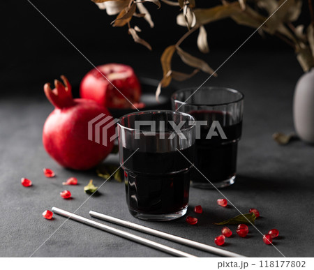 Natural pomegranate juice in a glasses on a dark background with fresh fruit and bouquet. Natural pomegranate juice in a glasses on a dark background with fresh fruit and bouquet. 118177802