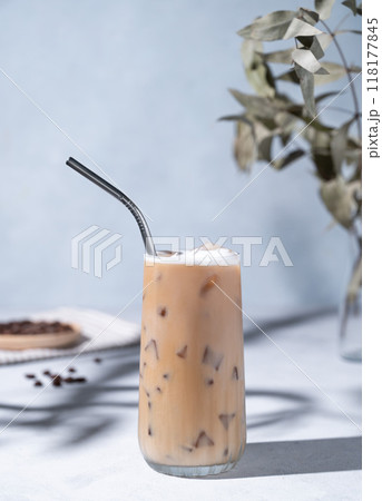 Iced coffee latte in a tall glass with milk on a light background with coffee beans, branch  118177845